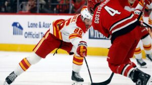 Calgary Flames' Joel Farabee (86) stretches for the puck as he approaches Carolina Hurricanes' Shayne Gostisbehere (4) during the first period of an NHL hockey game in Raleigh, N.C., Sunday, Nov. 30, 2025. (Karl DeBlaker/AP)