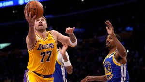 Los Angeles Lakers forward/guard Luka Doncic, left, shoots as Golden State Warriors guard De'anthony Melton defends during the first half of an NBA basketball game Wednesday, Oct. 21, 2026, in Los Angeles. (AP Photo/Mark J. Terrill)