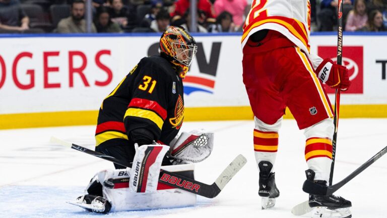 Vancouver Canucks goalie Leevi Merilainen stops the puck as Calgary Flames' Matvei Gridin (92) screens him during the second period of an NHL hockey game, in Vancouver, on Saturday, Oct. 3, 2026. Jacob Mallari/CP