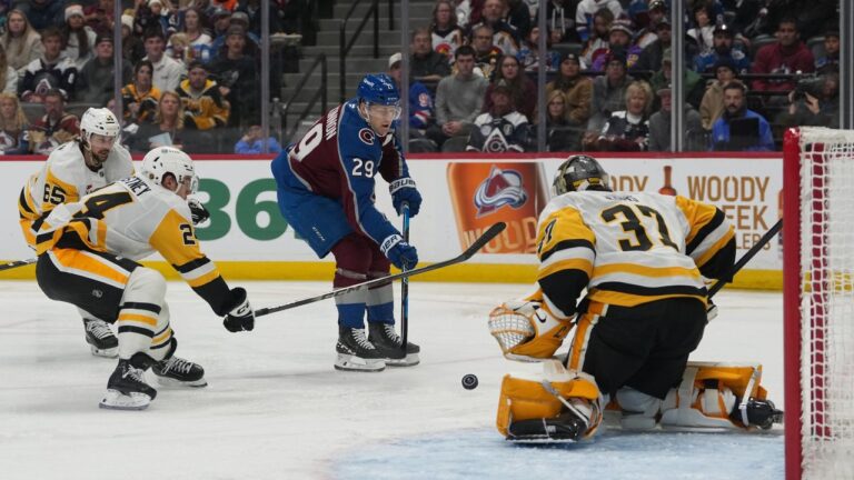 Colorado Avalanche centre Nathan MacKinnon, centre, drives past Pittsburgh Penguins defencemen Spencer Stastney, front left, and Erik Karlsson, back left, to shoot against Penguins goaltender Arturs Silovs, right, in the third period of an NHL hockey game, Friday, Oct. 16, 2026, in Denver. (David Zalubowski/AP)