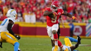 Kansas City Chiefs running back Kenneth Walker III (9) escapes a tackle attempt by Los Angeles Chargers linebacker Del'shawn Phillips, bottom, as Cam Hart (20) moves in to make this stop during the second half of an NFL football game in Kansas City, Mo., Sunday, Oct. 18, 2026. (AP Photo/Ed Zurga)