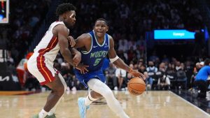 Minnesota Timberwolves guard Anthony Edwards (5) drives past Miami Heat guard Davion Mitchell during the second half of an NBA basketball game, Wednesday, Oct. 21, 2026, in Miami. (AP Photo/Rebecca Blackwell)
