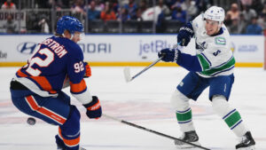 Vancouver Canucks' Zeev Buium (8) shoots the puck past New York Islanders' Simon Holmstrom (92) during the first period of an NHL hockey game Tuesday, Oct. 13, 2026, in Elmont, N.Y. (Frank Franklin II/AP)