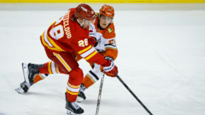 Anaheim Ducks' Judd Caulfield, right, checks Calgary Flames' Zach Whitecloud during second period NHL hockey action in Calgary on Saturday, Oct. 10, 2026. (Jeff McIntosh/CP)