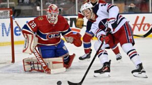 Montreal Canadiens' goaltender Jacob Fowler (32) keeps his eyes on the puck as Winnipeg Jets' Dawson Mercer (19) get ready to take a shot during third period NHL Heritage Classic action in Winnipeg on Sunday, Oct. 25, 2026. (Fred Greenslade/THE CANADIAN PRESS)