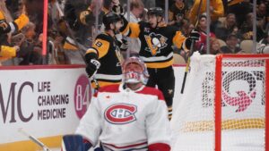 Pittsburgh Penguins' Tommy Novak (18) celebrates his goal with Egor Chinakhov, right rear, as Montreal Canadiens goaltender Jakub Dobes, foreground, collects himself during the second period of an NHL hockey game in Pittsburgh, Saturday, Oct. 3, 2026. (Gene J. Puskar/AP Photo)