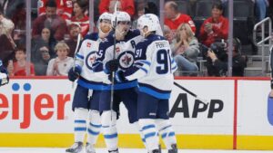 Winnipeg Jets centre Cole Perfetti (91) celebrates after his goal against the Detroit Red Wings with left wing Kyle Connor, left, and centre Mark Scheifele (55) during the first period of an NHL hockey game Sunday, Oct. 4, 2026, in Detroit. (Duane Burleson/AP)