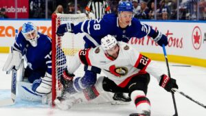 Toronto Maple Leafs' Troy Stecher (28) checks Ottawa Senators' Michael Amadio (22) as goaltender Sergei Bobrovsky (72) looks on during first period NHL hockey action in Toronto on Saturday, Oct. 3, 2026. (Frank Gunn/THE CANADIAN PRESS)