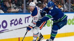 Vancouver Canucks' Luke Schenn (2) tries to check Edmonton Oilers' Connor McDavid (97) during second period NHL hockey action in Vancouver, B.C., on Thursday, Oct. 1, 2026. (Rich Lam/THE CANADIAN PRESS)