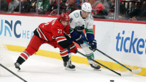 Carolina Hurricanes' Logan Stankoven (22) battles for the puck with Vancouver Canucks' Zeev Buium (8) during the second period of an NHL hockey game in Raleigh, N.C., Thursday, Oct. 8, 2026. (AP Photo/Karl DeBlaker)