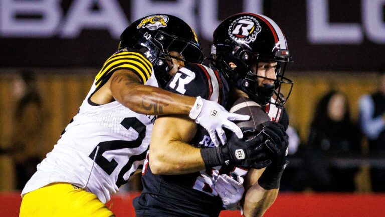 Ottawa Redblacks wide receiver Cade McDonald (right) catches the ball under pressure from Hamilton Tiger-Cats defensive back Devodric Bynum (20) during first half CFL action in Ottawa, on Friday, Oct. 2, 2026. (Keito Newman/THE CANADIAN PRESS)