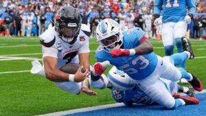 Houston Texans quarterback C.J. Stroud dives into the end zone for a touchdown after running the ball past Tennessee Titans safety Tony Adams and Anthony Hill Jr. during the second half of an NFL game in Nashville, Tenn., Sunday, Oct. 11, 2026. (AP/George Walker IV)