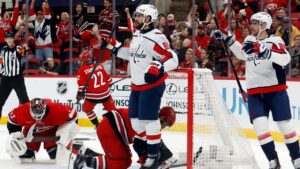 Washington Capitals' Alex Tuch (89) and Pierre-Luc Dubois, right, watch a replay of a goal as Carolina Hurricanes goaltender Brandon Bussi (32) and Sean Walker, center bottom, react during the first period of an NHL hockey game in Raleigh, N.C., Friday, Oct. 2, 2026. (Karl DeBlaker/AP Photo)